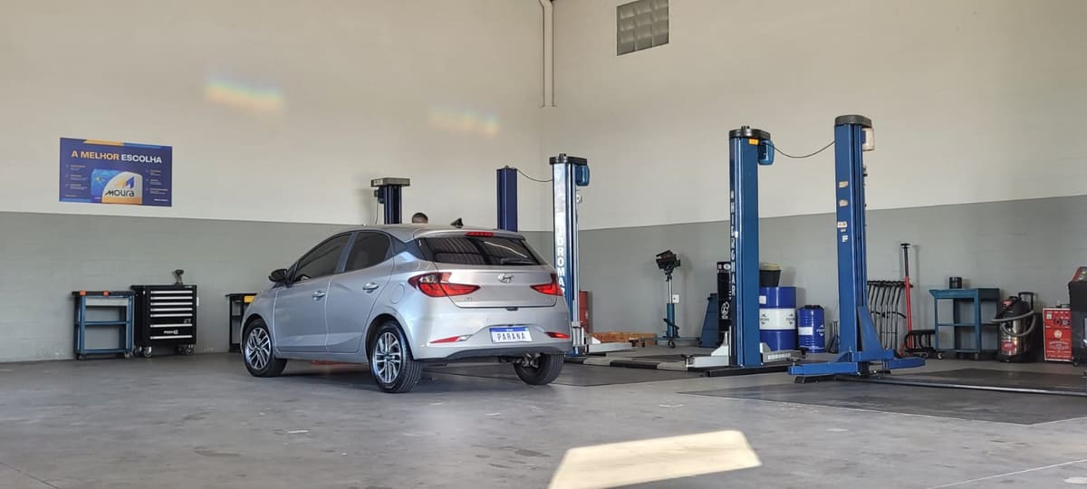 Interior da oficina Paraná Serviços Automotivos, com elevadores e veículo em manutenção